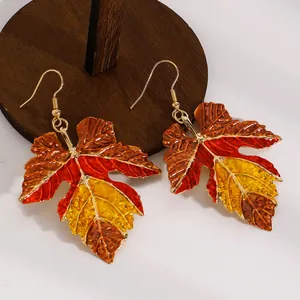 Detailed view of autumn-themed maple leaf earrings with vibrant enamel finish.