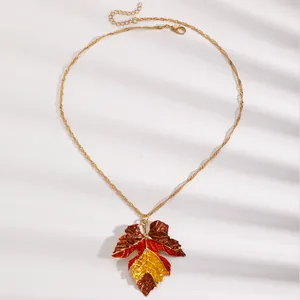 Detailed view of a vintage multi-color maple leaf pendant necklace on a clean white surface.