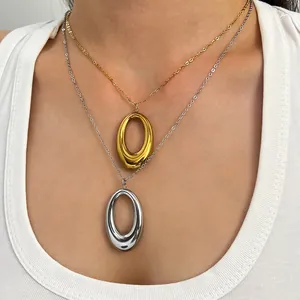 Close-up of layered gold and silver horseshoe necklaces worn on a white ribbed top.