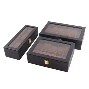 Three black lacquered wooden watch display boxes with clear glass lids and gold latches