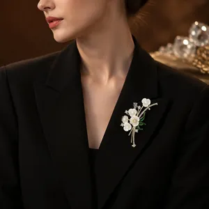 Eleganter Blumen-Emaille-Anstecker mit weißen Blüten an einem schwarzen Blazer-Sakko.