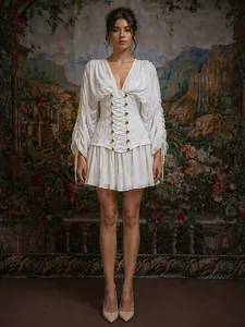 Detalle de mini vestido blanco con cuello en V, cintura de corsé y mangas de tul plisado