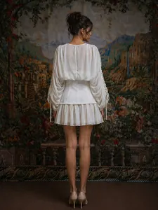 Vista trasera de mini vestido blanco de malla con mangas plisadas y cintura entallada
