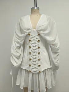 Detalle de vestido de corsé de malla blanca con botones dorados y cordones