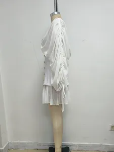 Vista lateral de un elegante minivestido blanco con mangas fruncidas y cordones