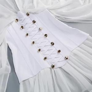 Detalle de vestido de malla plisada blanca con cintura corsé y botones dorados.