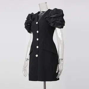 Detail view of black V-neck blazer dress featuring puff sleeves and rhinestone buttons.