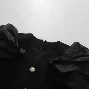 Detailed view of elegant black blazer dress with puff sleeves and pearl button.