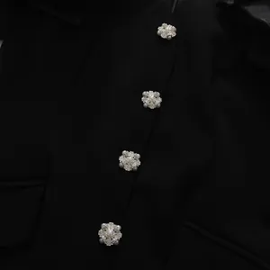 Close-up detail showing elegant silver snowflake rhinestone buttons on a black dress