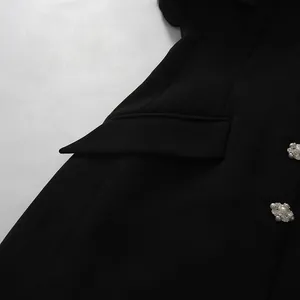 Close-up of elegant black blazer dress featuring ornate diamond and pearl buttons