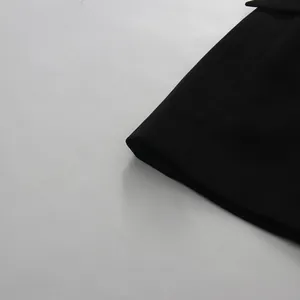 Macro detail of high-quality black fabric on an elegant V-neck suit dress with pleated design