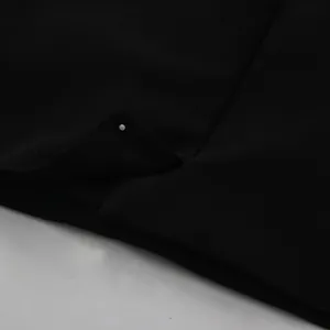 Detailed macro view of an elegant pearl button and pleated fabric on a black blazer dress