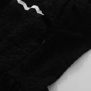 Detalle del vestido negro texturizado con borde ondulado blanco y cremallera invisible