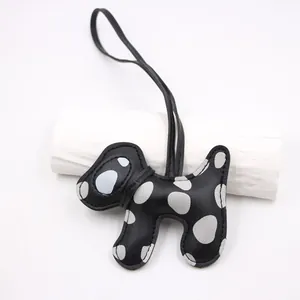 Close-up detail of a handmade black leather dog keychain with grey polka dot pattern