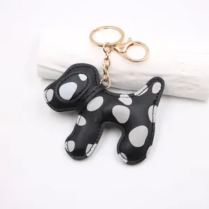 Detail of a Dalmatian dog-shaped leather keychain with polka dots and gold clasp.