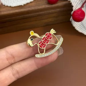 Exquisite goldene Schaukelpferd-Brosche mit roter Emaille und glänzenden Strasssteinen.