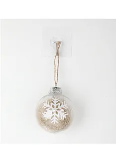 Clear Christmas ornament ball with white snowflake pattern and gold tinsel filling