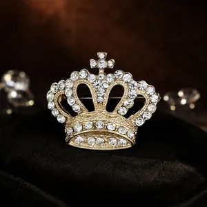 Elegant gold-tone crown brooch with shimmering rhinestones for women's apparel.