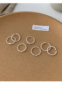 Nahaufnahme von sieben silbernen Stapelringen mit verschiedenen künstlerischen Designs