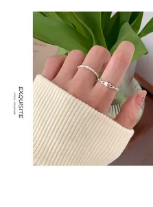 Nahaufnahme von minimalistischen Silberringen mit Herzmotiv an einer Hand mit Pullover