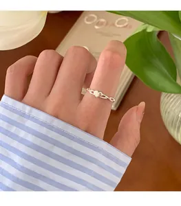 Detailansicht eines zarten, silbernen, herzförmigen Stapelrings, der am Finger getragen wird