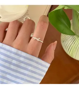 Detailaufnahme eines silbernen Schleifenrings am Finger mit gestreiftem Ärmel