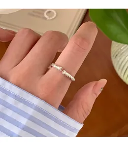 Detailansicht eines eleganten silbernen gedrehten offenen Rings am Finger mit Streifenärmel.