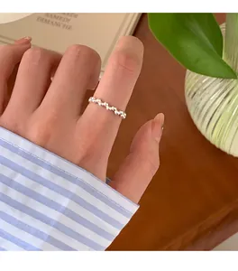 Nahaufnahme eines minimalistischen Silberperlenrings an einem Finger mit Streifenhemd