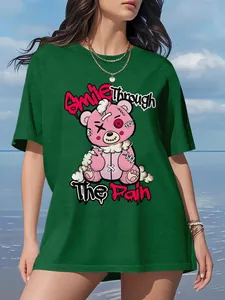 Detail view of green oversized T-shirt with pink stitched bear graphic and text