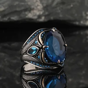 Detailed macro shot of vintage men's ring with oval blue sapphire and zircon accents
