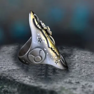 Close-up detail of a vintage silver ring featuring engraved Taurus zodiac and star symbols