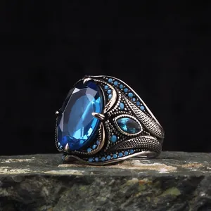 Close-up of retro men's ring featuring a large blue oval zircon and intricate carvings
