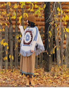 Vue détaillée du poncho en tricot à franges bohème dans un décor de forêt automnale