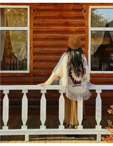 Détail de la vue arrière d'un poncho ethnique à franges dans un décor de chalet en bois