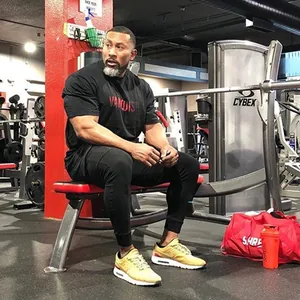 Gedetailleerd beeld van een gespierde man in een zwart fitness T-shirt in de gym.