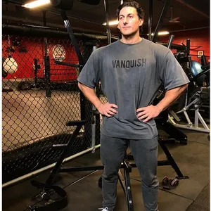 Grijs katoenen fitness t-shirt en broek voor heren gedragen door een model in een sportschool