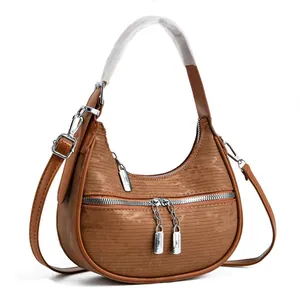 Close-up of a brown textured crescent shoulder bag with silver double zipper detail