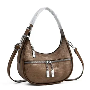Detailed view of brown crescent shoulder bag featuring corduroy texture and silver zippers