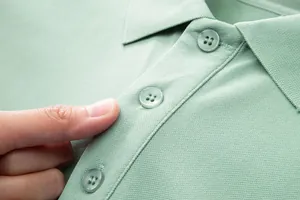 Macro shot of a mint green polo shirt showing the piqué fabric and button detail.