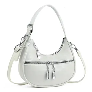 Detailed view of a white crescent shoulder bag with silver chain zippers and texture.