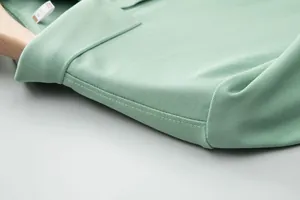 Close-up of light green pique polo shirt collar with neat stitching on wooden hanger.