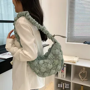 Side view of a mint green quilted cloud bag with ruffled shoulder strap worn by model