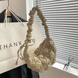 Detailed view of a beige quilted bubble cloud bag featuring a pleated handle and zipper