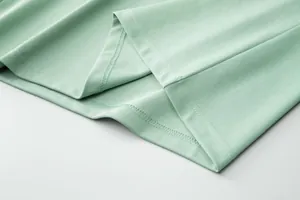 Detailed close-up view of precision hem stitching on a mint green mesh polo shirt