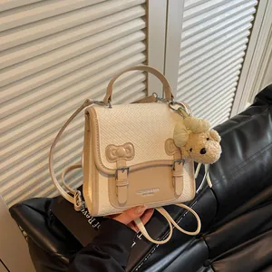 Close-up of a stylish woven cream and beige backpack featuring a cute bear plush charm