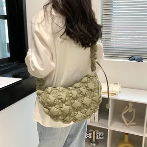 Detailed view of a light green bubble pleated cloud crossbody bag worn by a model