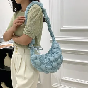 Close-up of light blue quilted bubble bag worn by a model in casual outfit