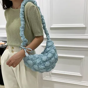Detail view of a light blue quilted bubble cloud bag worn by a model in casual style.