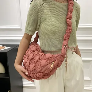 Close-up of pink bubble textured cloud bag worn as a stylish crossbody with green knit top