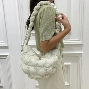 Detailed view of a white quilted bubble cloud bag worn over the shoulder by a model
